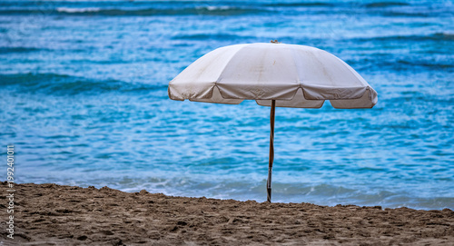 Lonely Beach Umbrella on a Deserted Beach with an Empty Ocean Background.