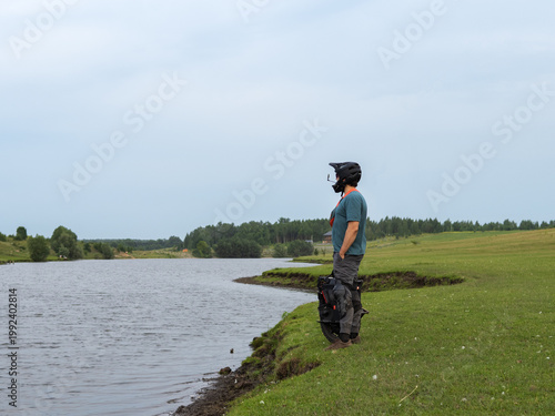 Modern eco-friendly individual transport, electric mono wheel. A man poses by the river on the background of a green field