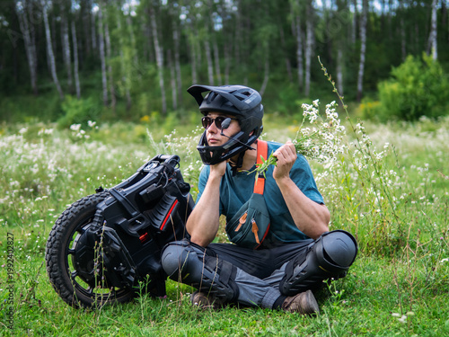 young man poses in nature next to a mono wheel. Modern eco-friendly transport.