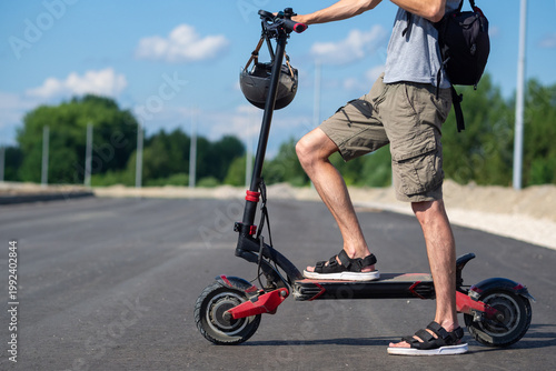 The legs of a man standing on an electric scooter. Popular summer urban electric transport.