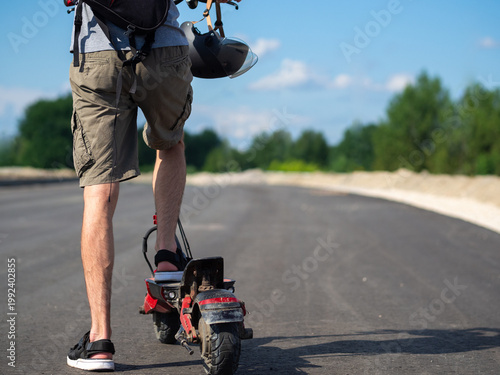 Legs of a man standing on an electric scooter, backpack on his back