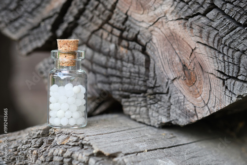 Homeopathic remedy in glass vial with sugar globules, natural medicine concept.