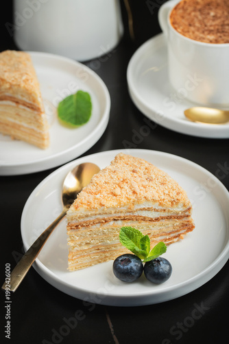 Medovik. Honey cake made from honey cakes with whipped sour cream, decorated with berries, pomegranate and flowers