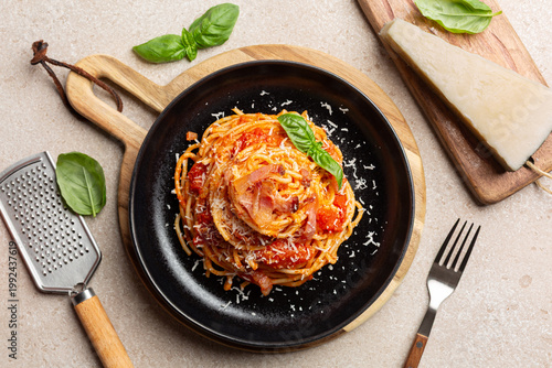 Obraz na plátně Top view of italian Pasta all'Amatriciana,  spaghetti, tomato sauce and crispy guanciale, cured pork cheek,  Pecorino Romano cheese and grater