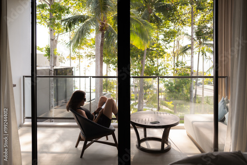 young woman sitting on a chair on a balcony oh the island of Koh Samui in Thailand.