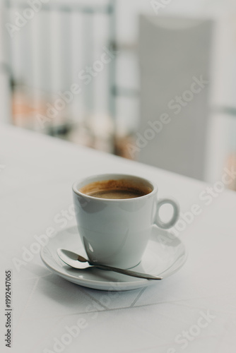 Cup of black coffee on a white table in a street cafe. Selective focus. Place for text.