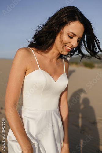 Bride smiling cheerfully enjoying windy day on sand dunes