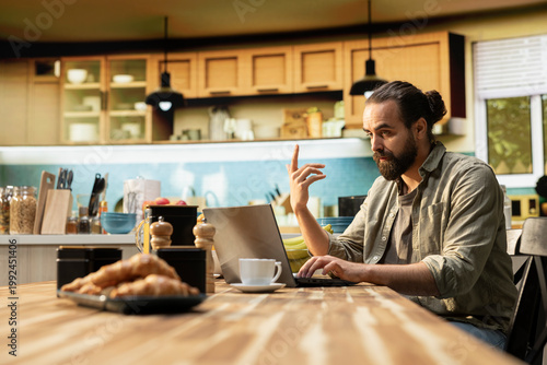 Confused preoccupied male, uncertain with remote work, laptop working from home, male freelancer unsure, frowning at the screen, ambiguous teleworking, unsure man in doubt.
