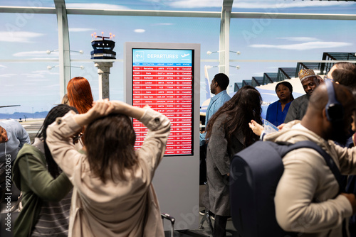 Canvas Print Passengers in airport worried about disruption causing delayed flights, reacting to red alert on airline screen