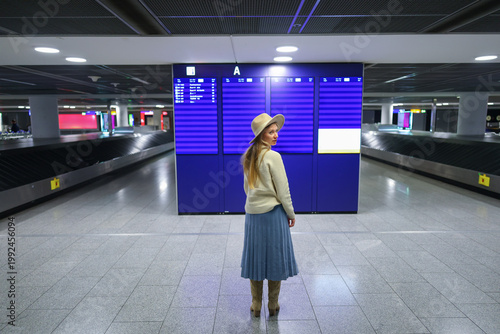 Traveler checking flight information display, modern airport interior scene.