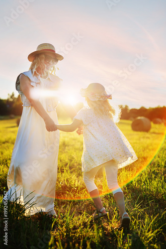 Rural summer fun, mother and daughter in straw hats laughing together.