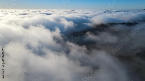 Aerial view looking down on a sea of dense, fluffy white clouds with a blue sky above