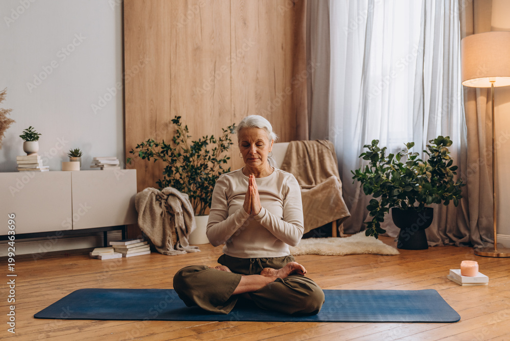 Obraz premium Focused senior woman enjoy yoga exercises practice in calm studio 