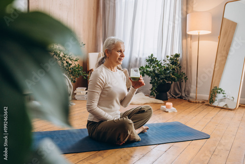 Senior lady with grey hair sips healthy organic beverage for wellness in living room