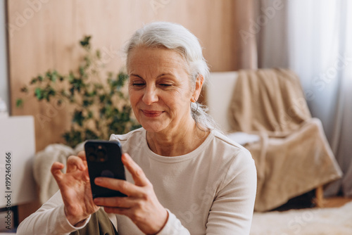 Senior woman smiles while holding smartphone during break