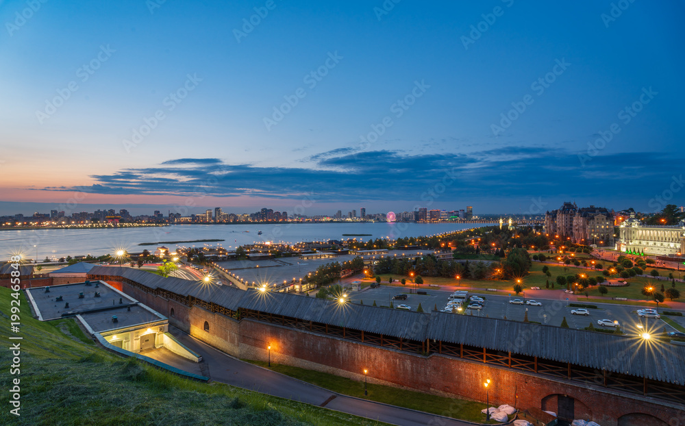 Fototapeta premium Night cityscape of the embankment of the city of Kazan. Illuminated buildings and lanterns on the river bank