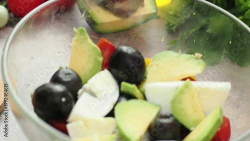 A girl prepares a delicious, low-calorie, and healthy salad. Keto diet. Balanced protein and fat, high in fiber. Salad with avocado, greens, bell pepper, egg, olives, parsley, and dill, tomatoes