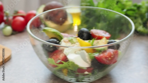 A girl prepares a delicious, low-calorie, and healthy salad. Keto diet. Balanced protein and fat, high in fiber. Salad with avocado, greens, bell pepper, egg, olives, parsley, and dill, tomatoes