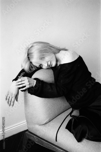 Blonde Curled Over Chair Arm in Black Outfit, B&W Portrait