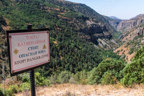Close-up of a sign warning of danger, in three languages, near the edge of Aksu canyon, in southern Kazakhstan.