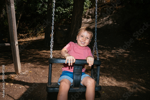 Young boy having fun smiling on swing
