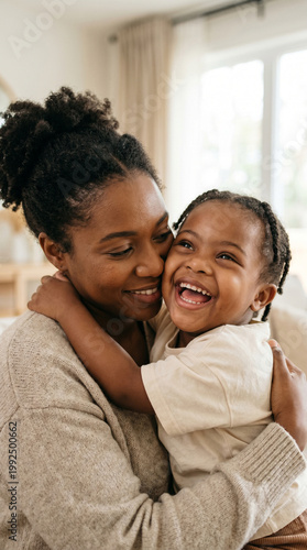 African American mother and her young daughter with Down syndrome sharing a warm hug indoors, inclusive family lifestyle.