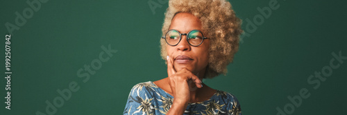 Pretty girl in glasses dressed in a blue t-shirt thinks about something tries to make a decision in mind isolated on green-blue background. Panoramic