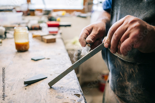 Craftsman filing metal blade shaping handmade knife