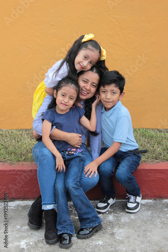 25-year-old Latina mother with her two daughters and son show their love with kisses and hugs to celebrate Mother's Day