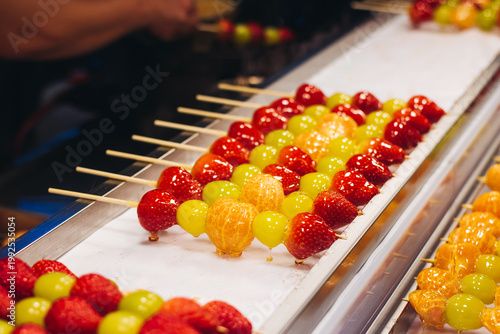 Ddalgi Satang, Fruit Hard Candy on stick skewers, candied strawberry, grape and tangerine in hardened sugar, traditional street food selection, Seoul, South Korea, local tasty dishes on night market