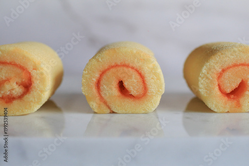 Homemade orange yam rolls on marble table. Soft cake texture. Dessert and bakery.