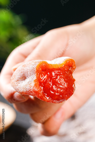 Hand Holding Orange Gummy Bear Candy with Translucent Chewy Texture
