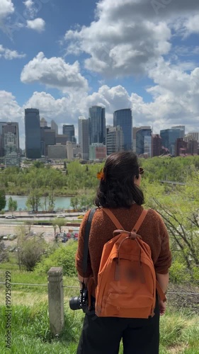 Woman with backpack and camera observing Calgary skyline and Bow River landscape in Alberta, Canada