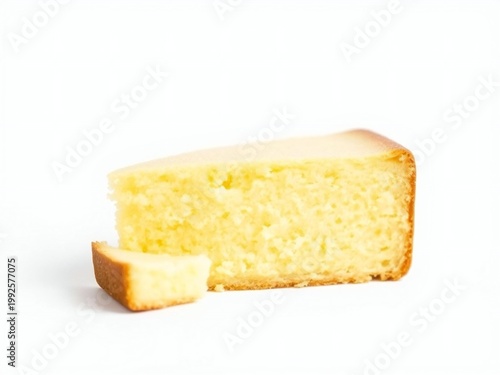 A slice of plain yellow cake with a piece broken off on a white background