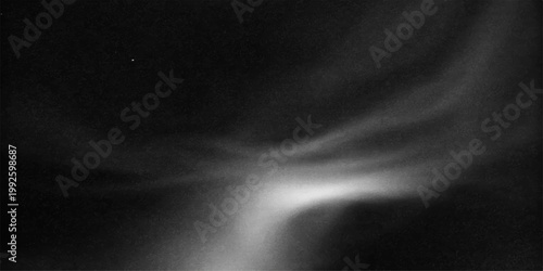 A dark texture of black and white smoke swirls like a misty storm cloud against a black background to create a motion design pattern of wind and light