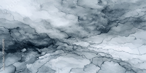 An aerial view of the high winter landscape shows white snow on the mountains under a blue sky with clouds in the atmosphere