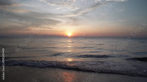 Peaceful Sunrise Over Calm Tropical Beach with Soft Waves and Golden Sky Reflection on Sand