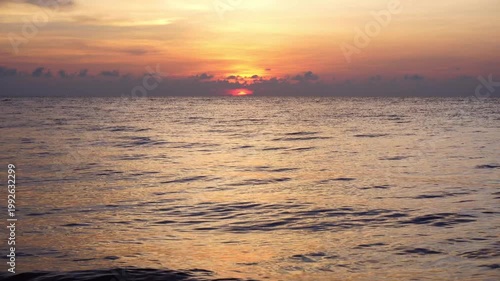 Vivid Orange and Red Sunset Over Open Sea with Glowing Sky and Golden Light Reflected on Water