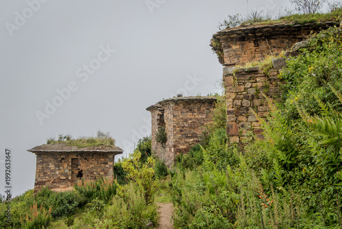 Ancient Stone Houses on Mountain Path with Lush Vegetation and Copy Space