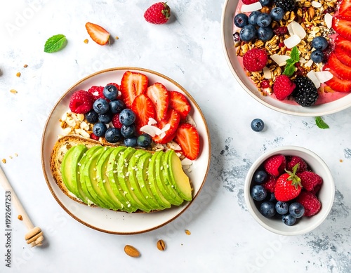 A delicious and healthy breakfast spread featuring avocado toast with fresh berries and granola on a marble countertop