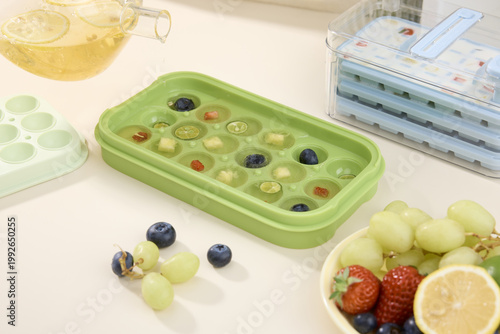 фотографія Fruit tea ice cubes with berries and grapes in silicone tray on kitchen counter
