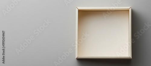 Empty open rectangular beige box on a clean gray background, viewed from above with ample copy space for text or design.