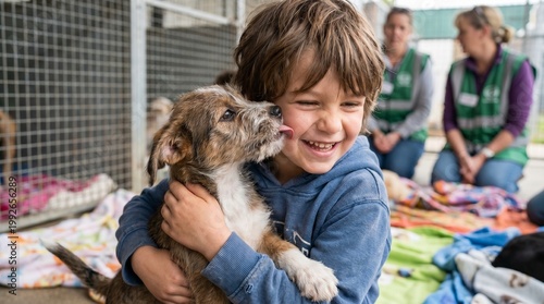Joyful young boy receives a loving lick from an adorable puppy while hugging it at an animal rescue center.