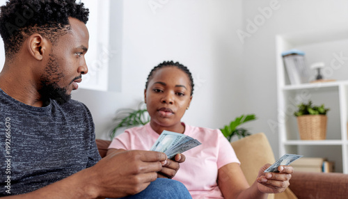 Young African American couple feeling stressed and anxious while checking bank balance and managing household finance debt with worried facial expression in their living room at home