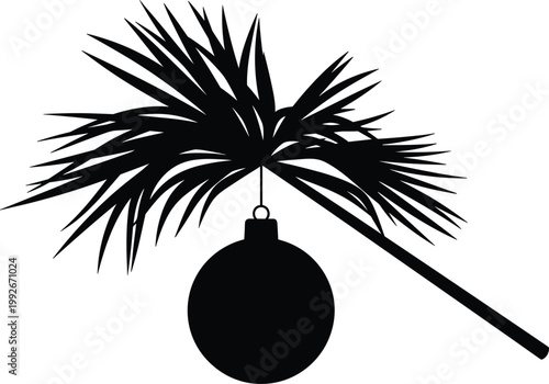 Black silhouette of a christmas bauble ornament hanging from a tropical palm tree leaf
