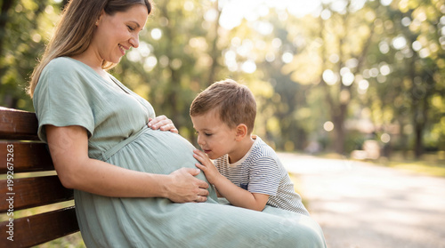 Mother's Day expectant mother with toddler son on park bench showing sibling anticipation connection for lifestyle magazine editorial content
