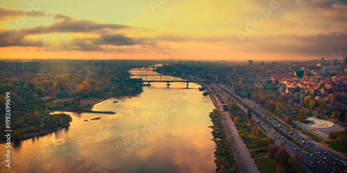 Aerial view of the Vistula River flowing through the city with historic bridges and autumn trees during a golden sunset Warsaw, Masovian Voivodeship, Poland.