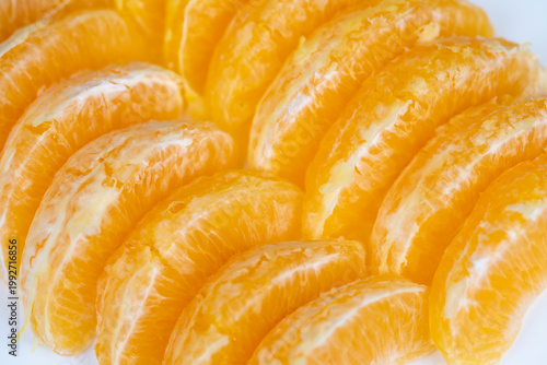 Photography Closeup bright orange segments arranged on white background, glistening with jui