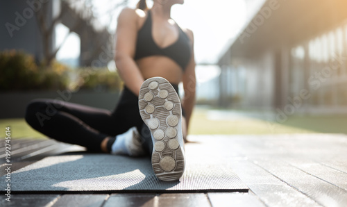 Obraz na płótnie Woman stretching outdoors on a yoga mat during workout, representing flexibility, balance, and a healthy active lifestyle in natural sunlight