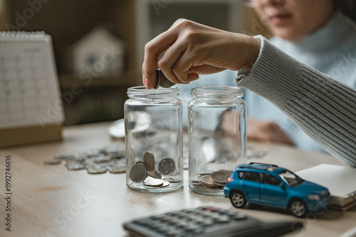 Fotografía Person putting coins into jars for emergency fund, representing savings planning, financial security, risk management, and personal finance preparation for future expenses and unexpected situations